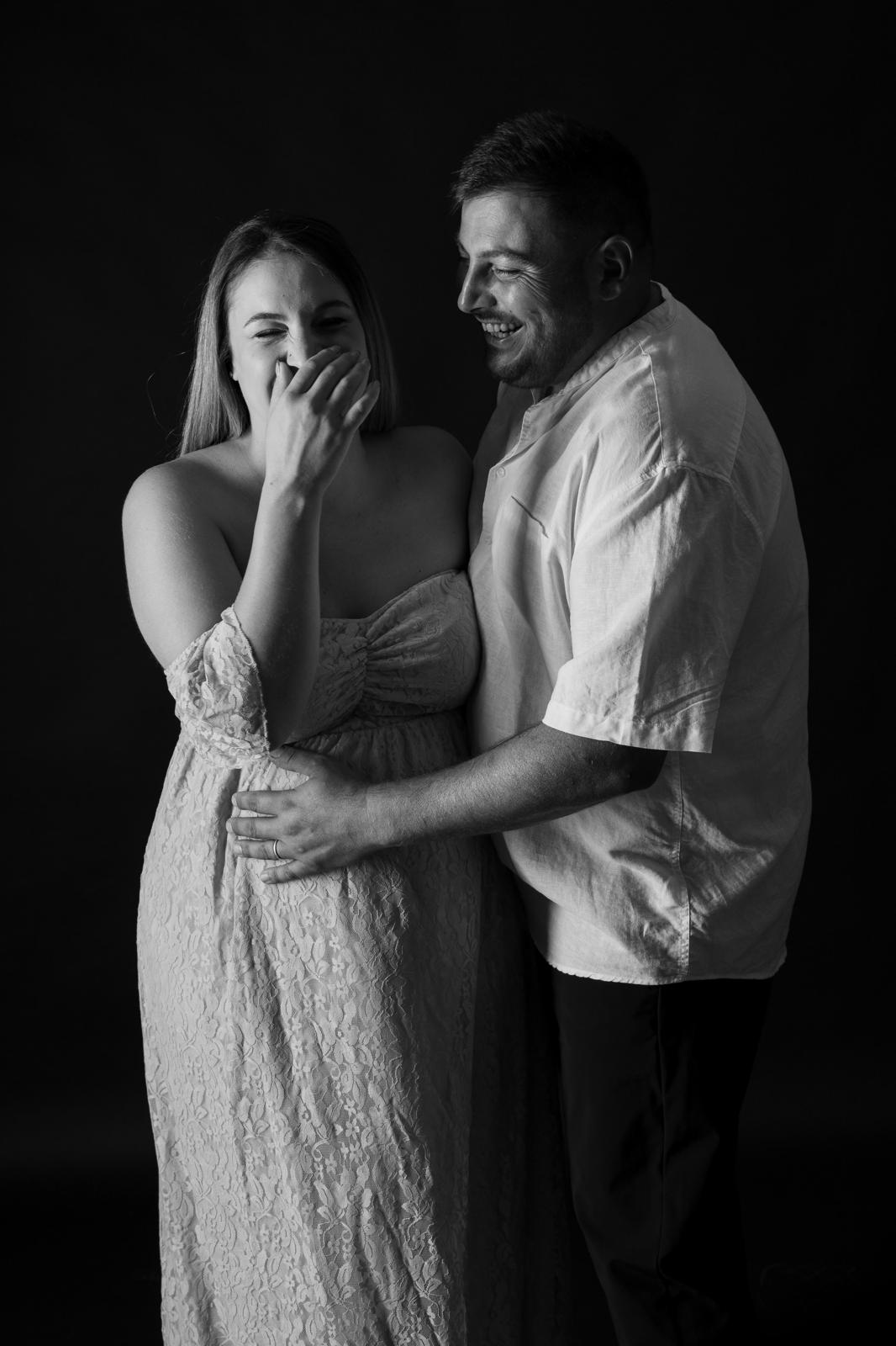 Coppia che ride durante lo shooting maternity, in bianco e nero