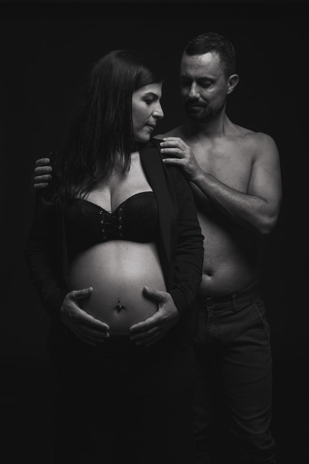 Coppia in posa intima, mani sulle spalle e sul pancione